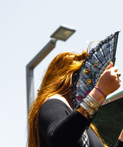 Rear view of woman using mobile phone against clear sky