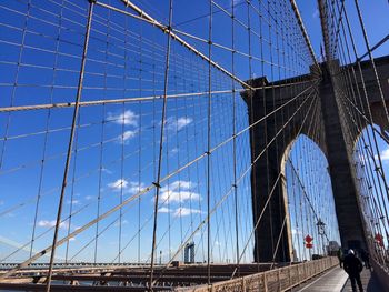 Low angle view of brooklyn bridge against blue sky on sunny day