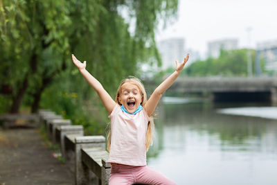 Happy little girl takes off protective medical mask from face outdoors. victory over coronavirus