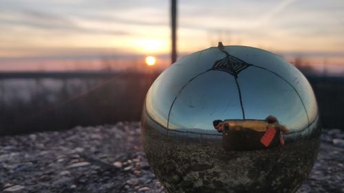 Close-up of sunglasses on beach against sky during sunset