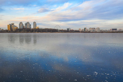 Scenic view of river by buildings against sky