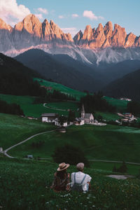 Rear view of people on field against mountain range