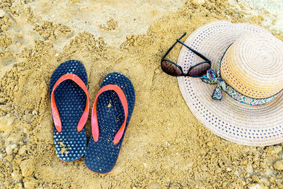 High angle view of flip-flops with sun hat and sunglasses on beach