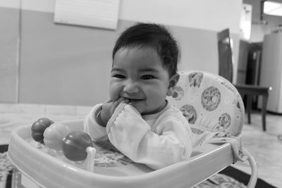 Cute boy with finger in mouth looking away in walker at home