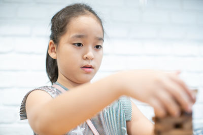 Close-up of girl playing block removal game against wall