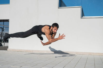 Side view of young man exercising on footpath