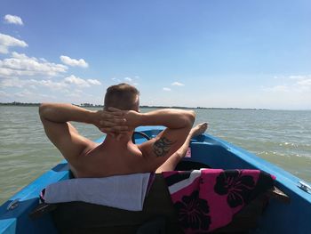 Man standing on boat in sea against sky