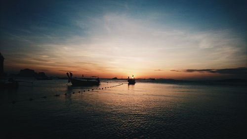 Silhouette boats moored on sea against sky during sunset