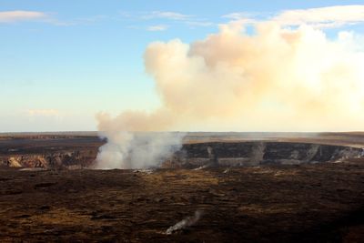 Steam emitting from volcanic crater against sky