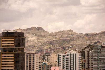 Buildings in city against cloudy sky