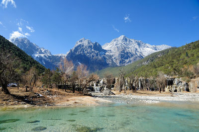 Scenic view of trees and mountains against blue sky