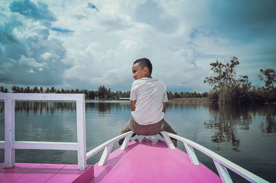 Side view of man standing by lake against sky