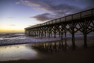 Silhouette pier on beach against sky during sunset