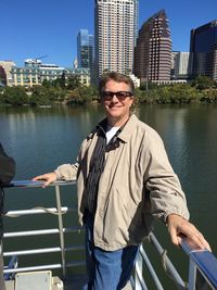 Portrait of smiling man standing by lake in city on sunny day