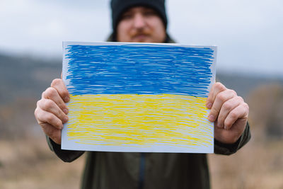 Ukrainian man holds a painted flag of ukraine. war of russia against ukraine.