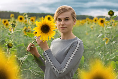 Portrait of young woman standing on sunflower field