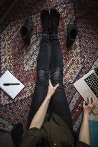 Low section of blogger using laptop while sitting on carpet