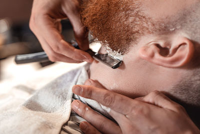 Barber shaving customers beard in salon