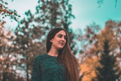 Young woman standing against sky