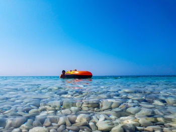 Water surface shot of siblings swimming in sea against clear blue sky during sunny day