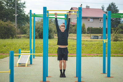 Goal-oriented blond boy builds the strength of his own body on the workout field