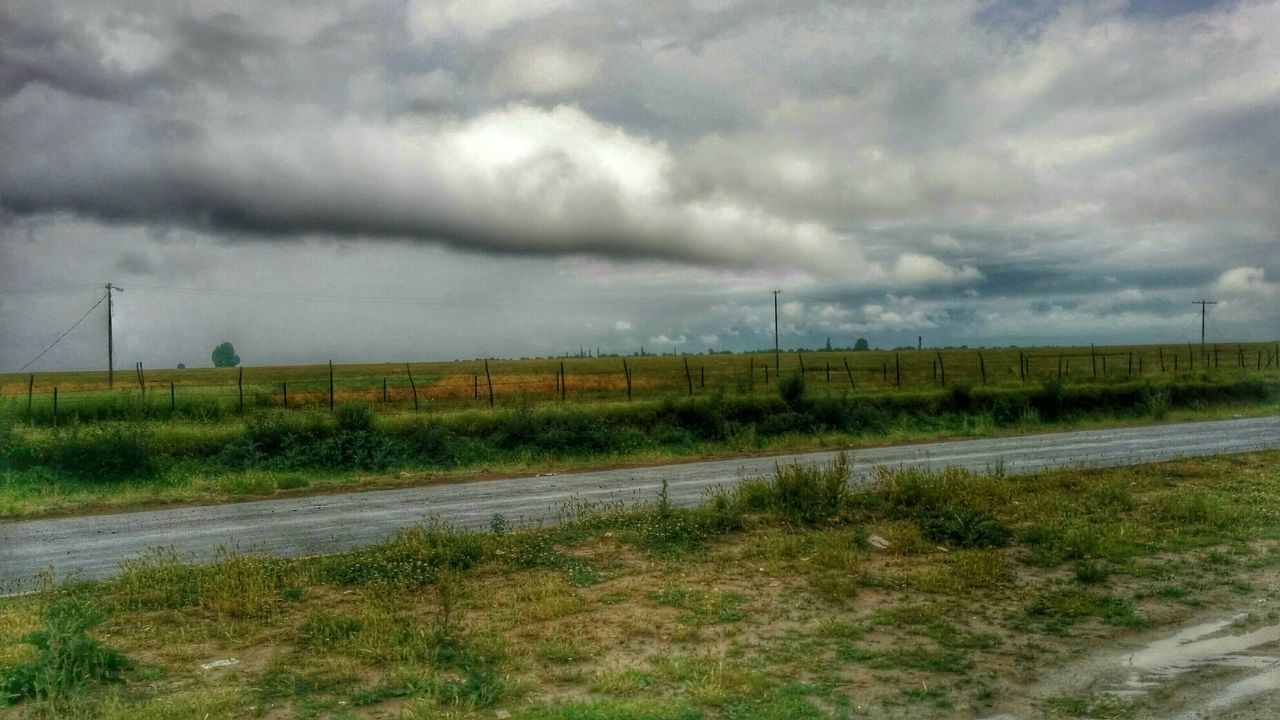 sky, field, landscape, cloud - sky, grass, cloudy, tranquil scene, tranquility, nature, rural scene, road, scenics, weather, the way forward, overcast, grassy, transportation, beauty in nature, cloud, agriculture