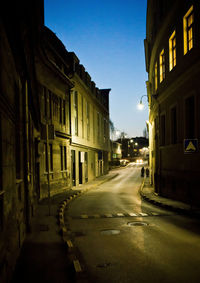 Empty road amidst buildings in city at night