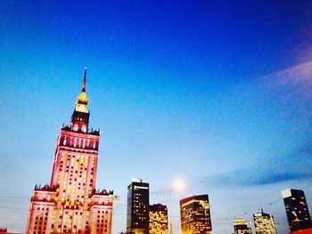 Low angle view of illuminated buildings against blue sky