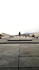 Rear view of man walking on street against clear sky