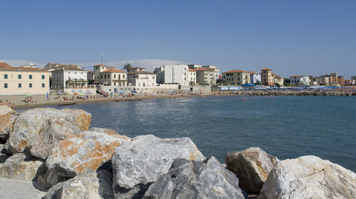 Sea by buildings against clear sky