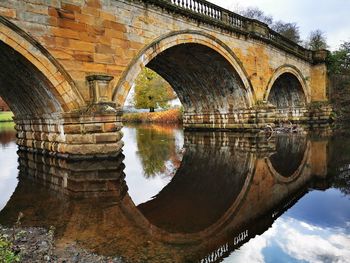 Arch bridge over river against sky