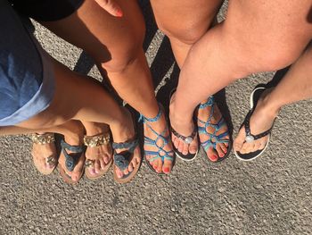 Low section of friends standing on road during sunny day