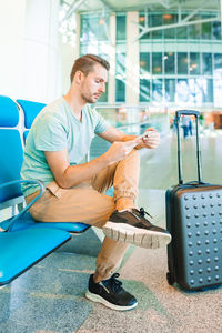 Man using mobile phone while sitting at airport