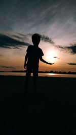 Silhouette man standing on field against sky during sunset