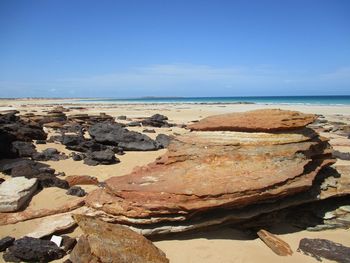 Rocks on beach against blue sky