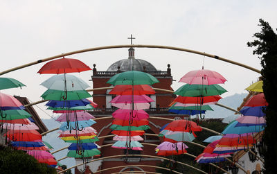 Low angle view of multi colored umbrellas by building against sky