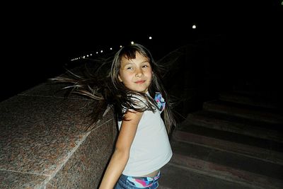 Portrait of girl standing against black background