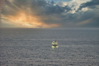 Boat sailing in sea against sky during sunset