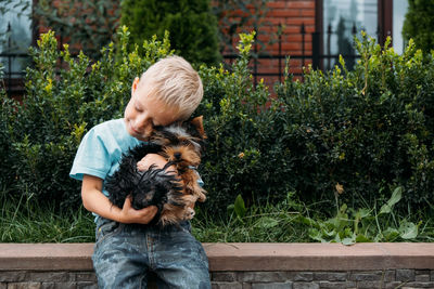 Boy with yorkshire terrier dog puppy. cute baby boy hugs york terrier puppy and siting