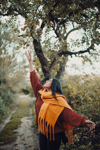 Woman standing by tree trunk