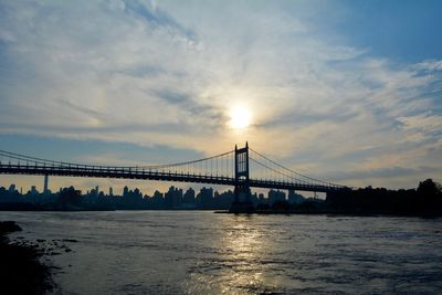 View of suspension bridge over river at sunset