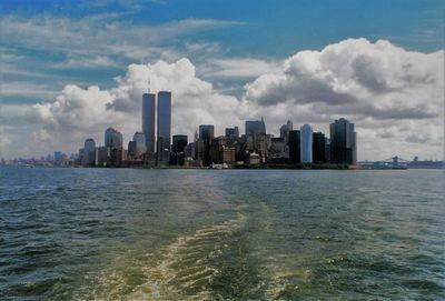 Sea by cityscape against sky