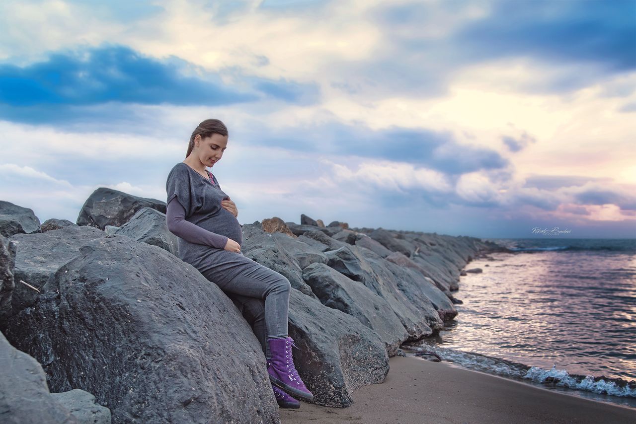 sky, cloud - sky, sea, water, rock, rock - object, solid, one person, beauty in nature, real people, leisure activity, lifestyles, beach, casual clothing, scenics - nature, full length, nature, sitting, outdoors