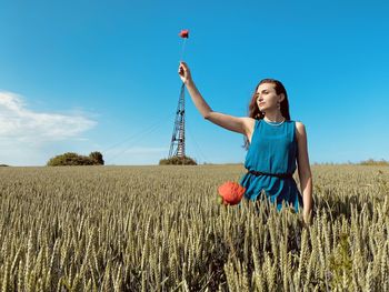 Rear view of young woman standing on field against sky