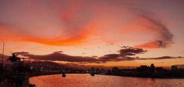 Scenic view of river against dramatic sky during sunset