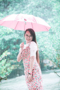Young woman with umbrella standing in rain during rainy season