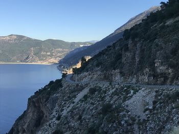 Scenic view of lake and mountains against clear blue sky