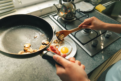 Cooking lovely breakfast set of sausages and fired egg in the kitchen in warm morning light.