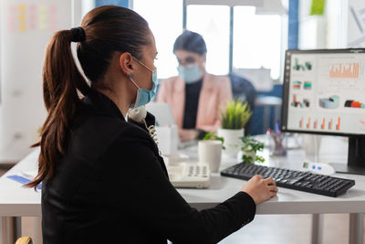 Side view of of businesswoman wearing mask working at office