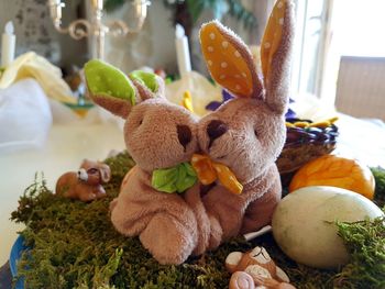 Close-up of stuffed easter bunnies next to easter eggs on moss